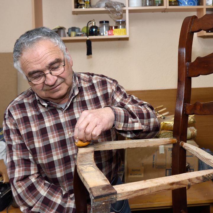 an old man repairing a broken chair