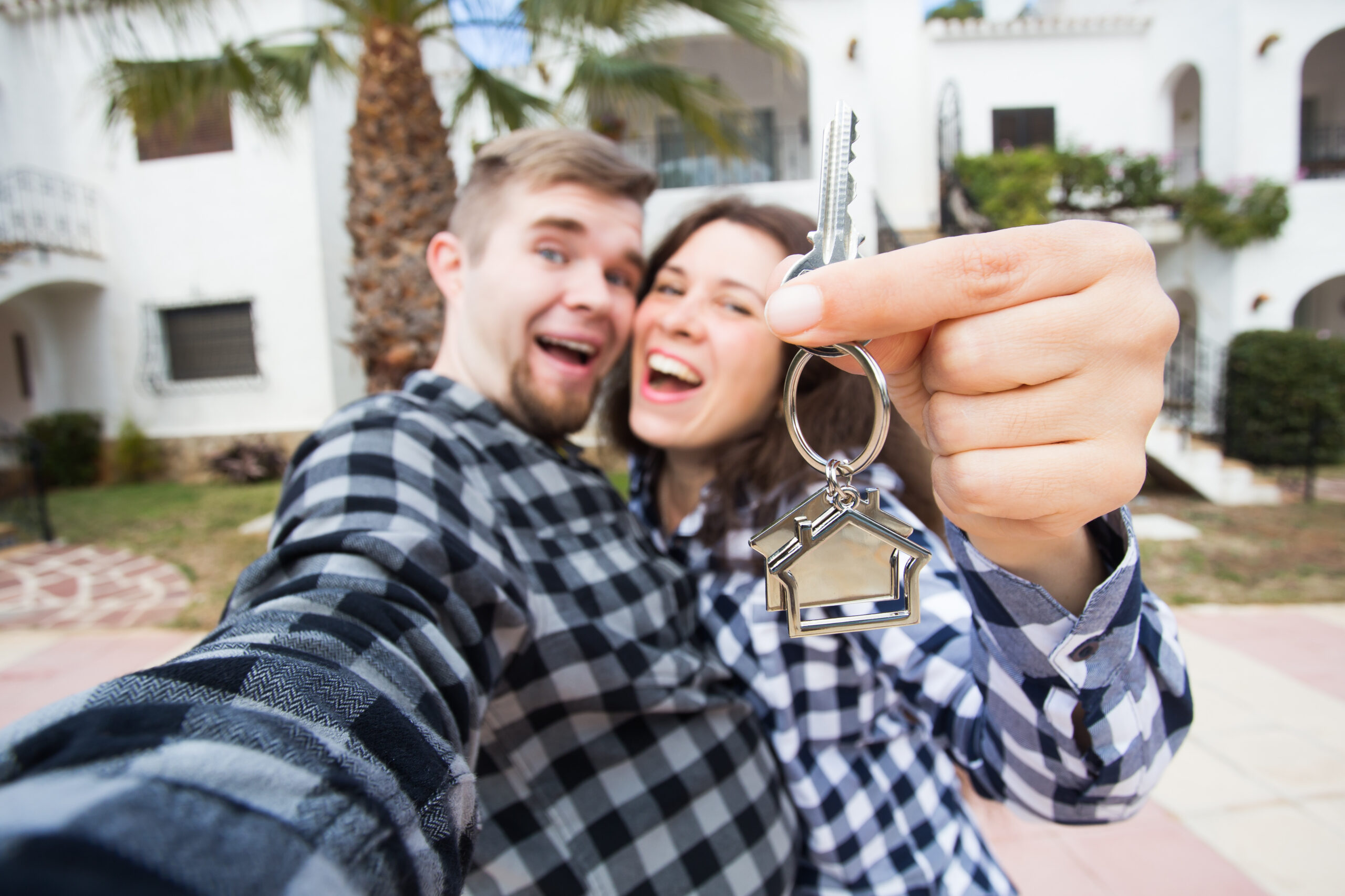 can i afford a second home - New Home, real estate and moving concept - Funny young couple showings keys from new house