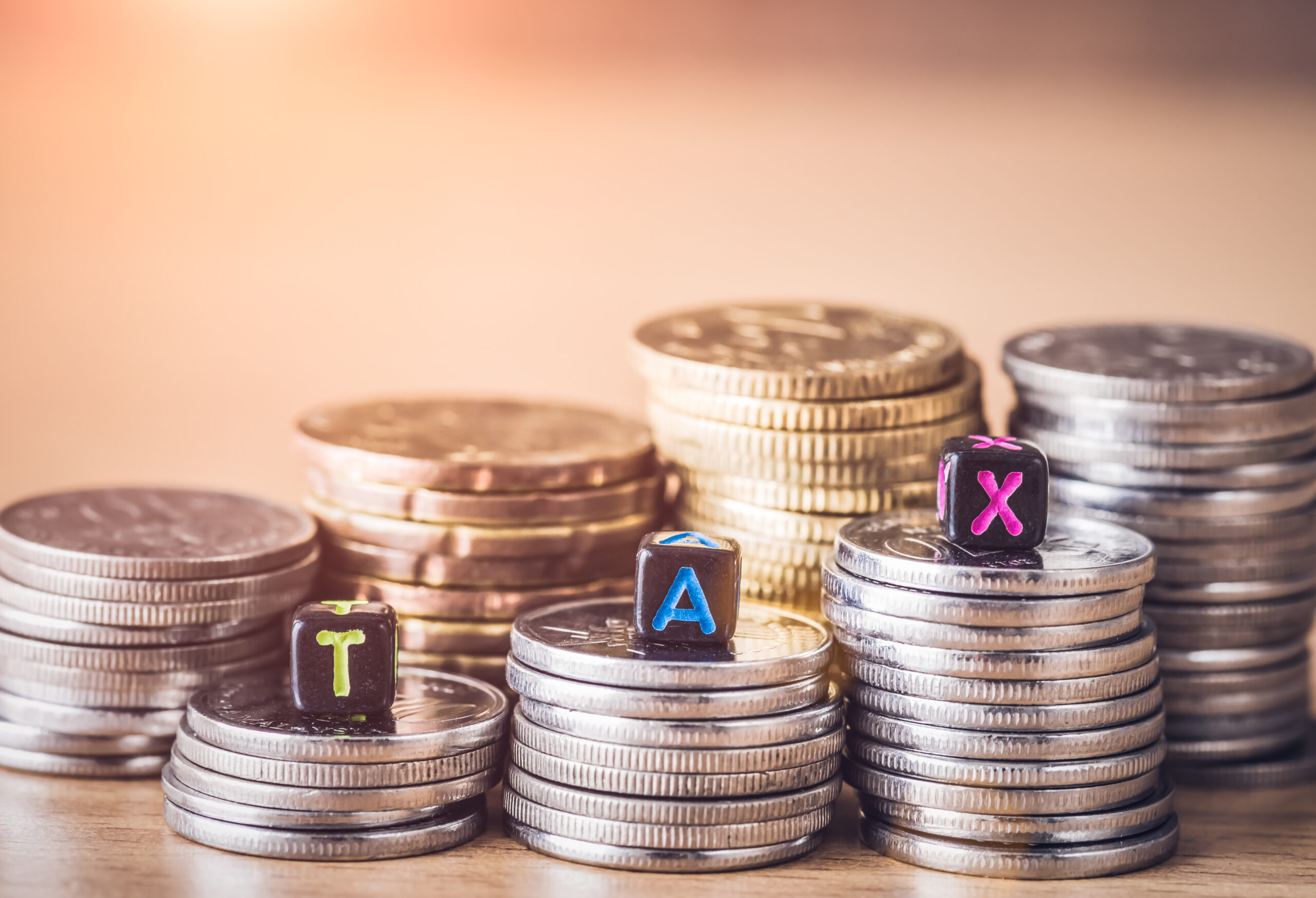 TAX Concept with alphabet block on a gold stacked of coins.