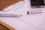 Checklist concept - checklist, paper and a pen with checklist word on wooden table