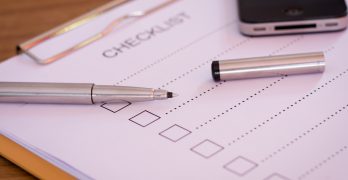 Checklist concept - checklist, paper and a pen with checklist word on wooden table