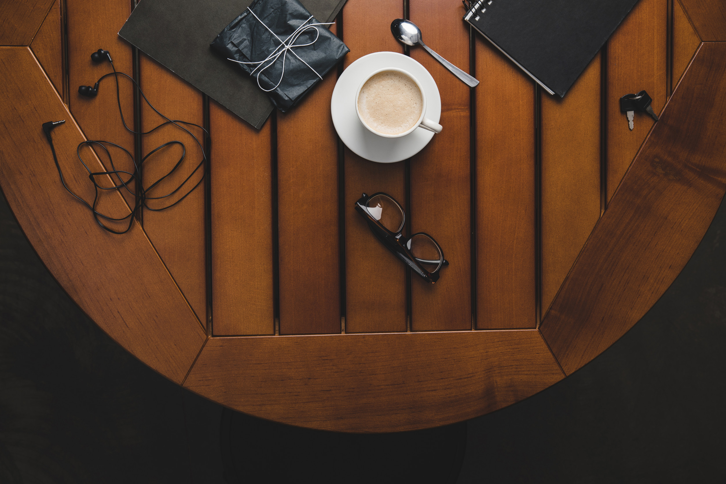 top view of coffee cup, eyeglasses and notepads on wooden table