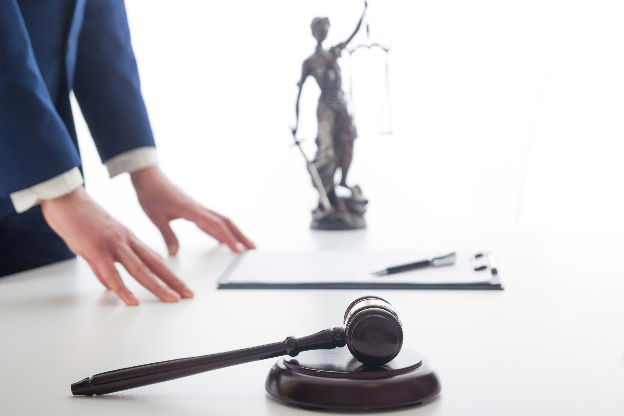 gavel, lady justice and man with hands on table