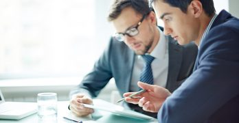 Two businessmen meeting in modern office with digital tablet