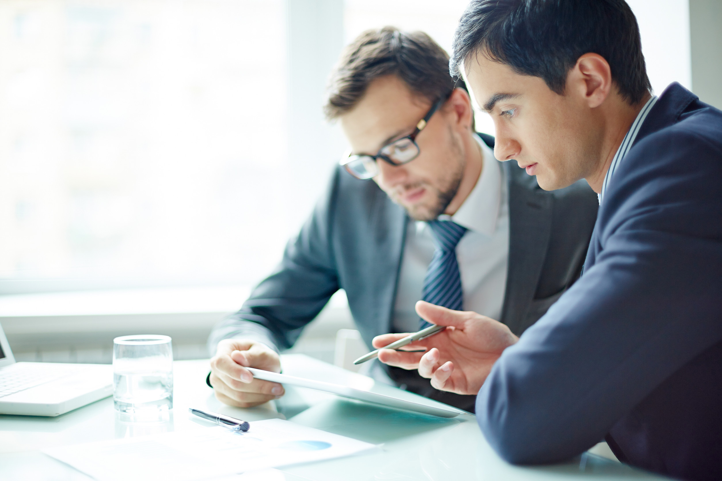 Two businessmen meeting in modern office with digital tablet