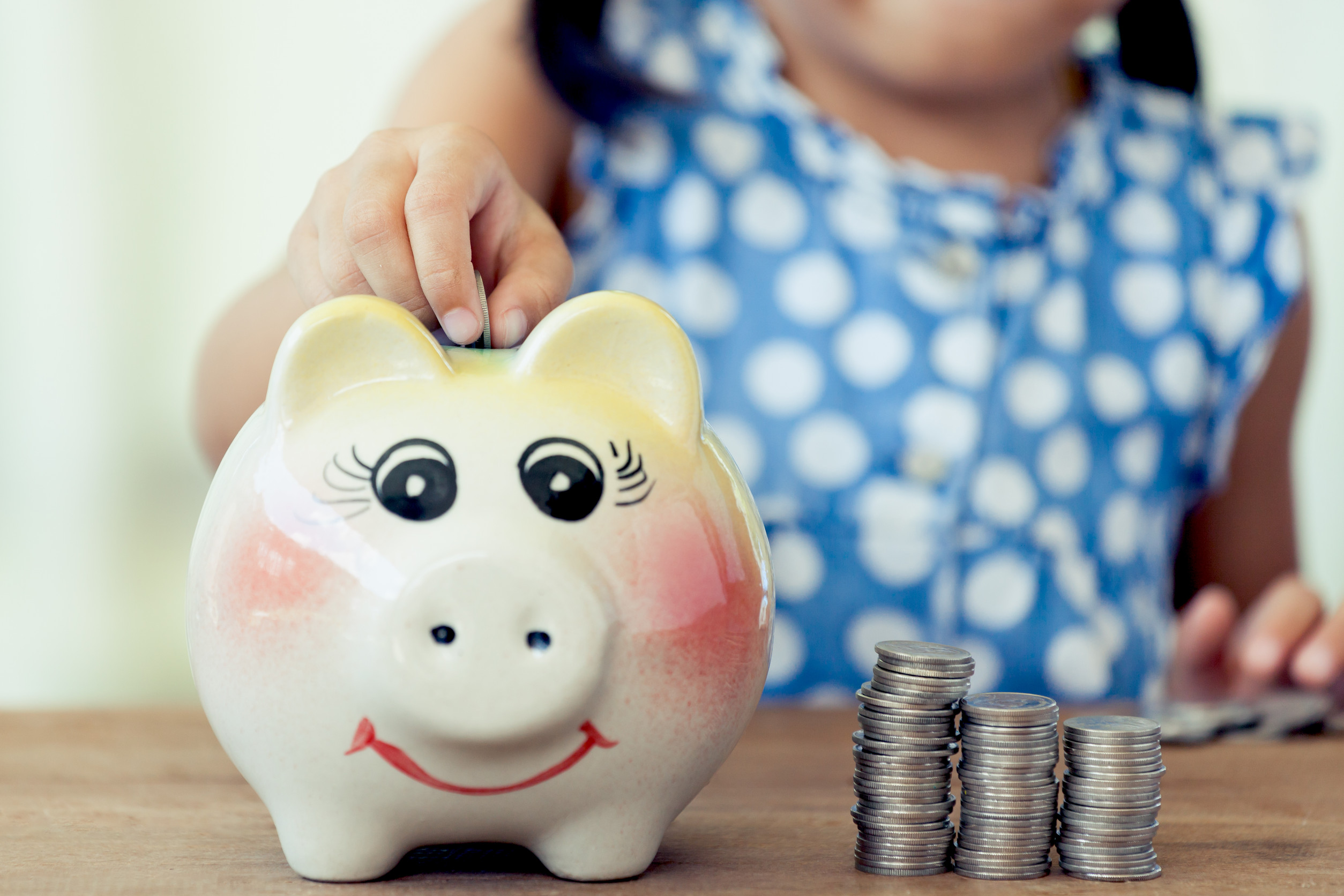 Child asian little girl putting coin into Piggy Bank in vintage color tone,kid saving money for the future concept