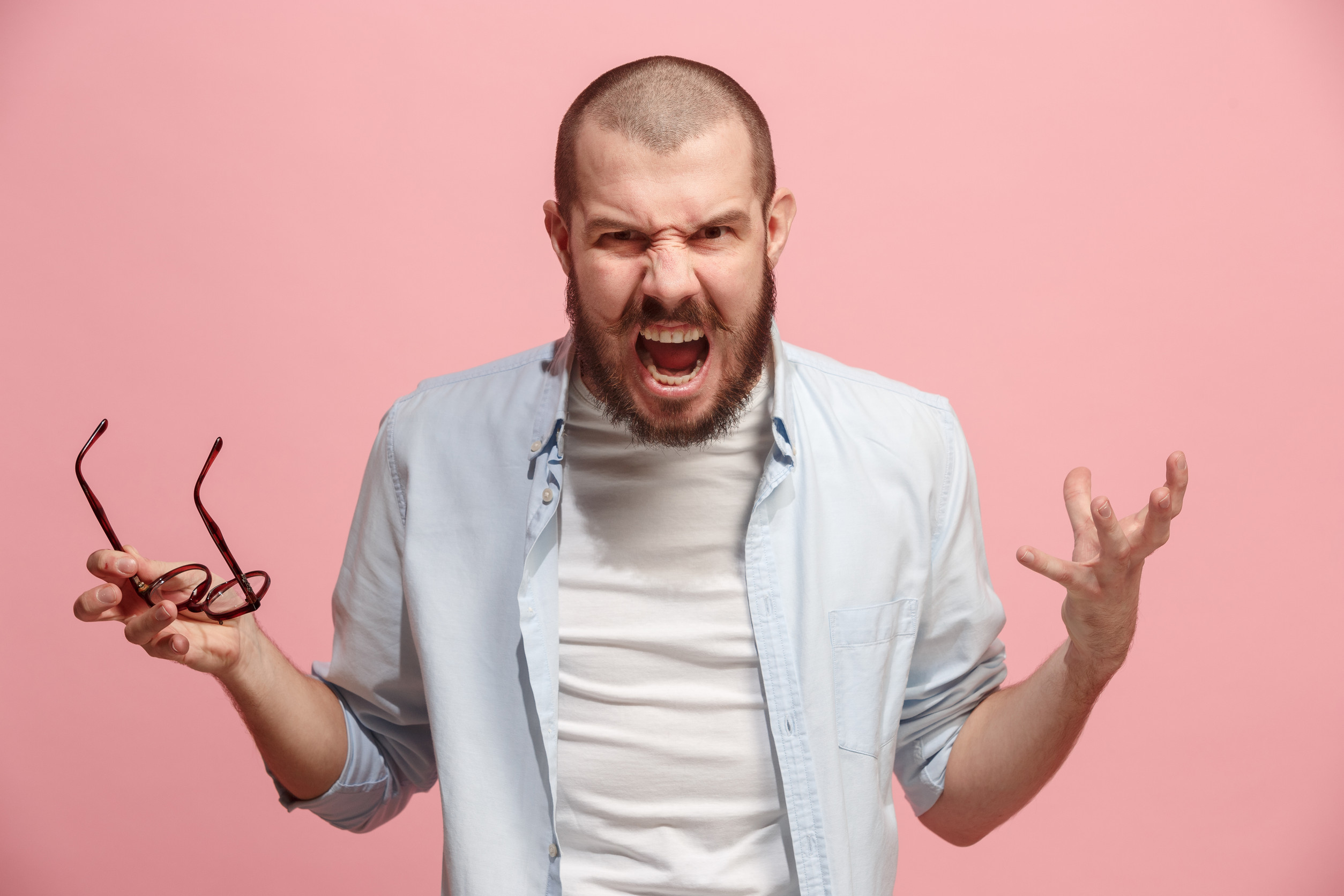 Screaming, hate, rage. Crying emotional angry man screaming on pink studio background. Emotional, young face. Female half-length portrait. Human emotions, facial expression concept. Trendy colors