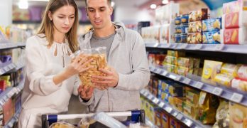 man with girlfriend shopping crackers and snacks in food department of supermarket