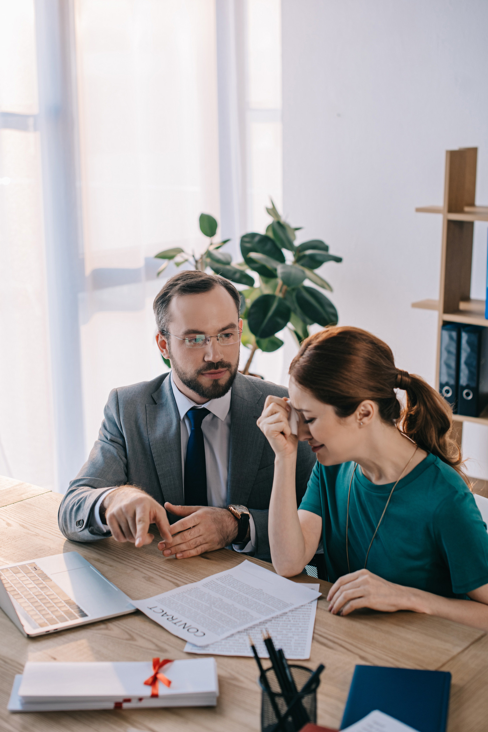 businessman and crying client discussing contract during meeting in office