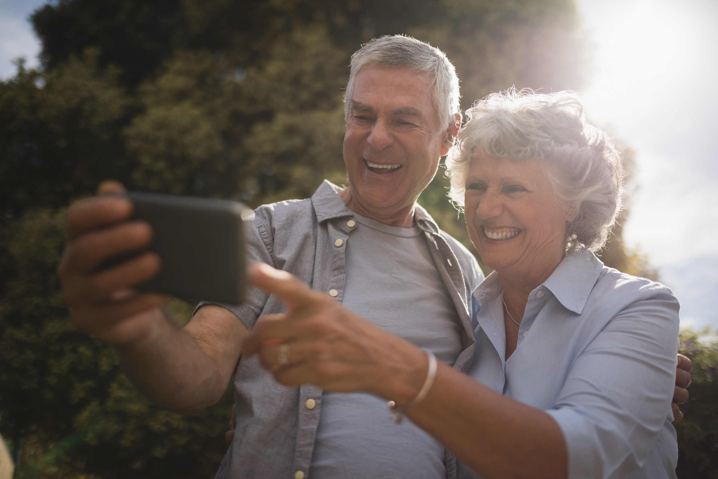 Happy senior couple looking at mobile phone on sunny day