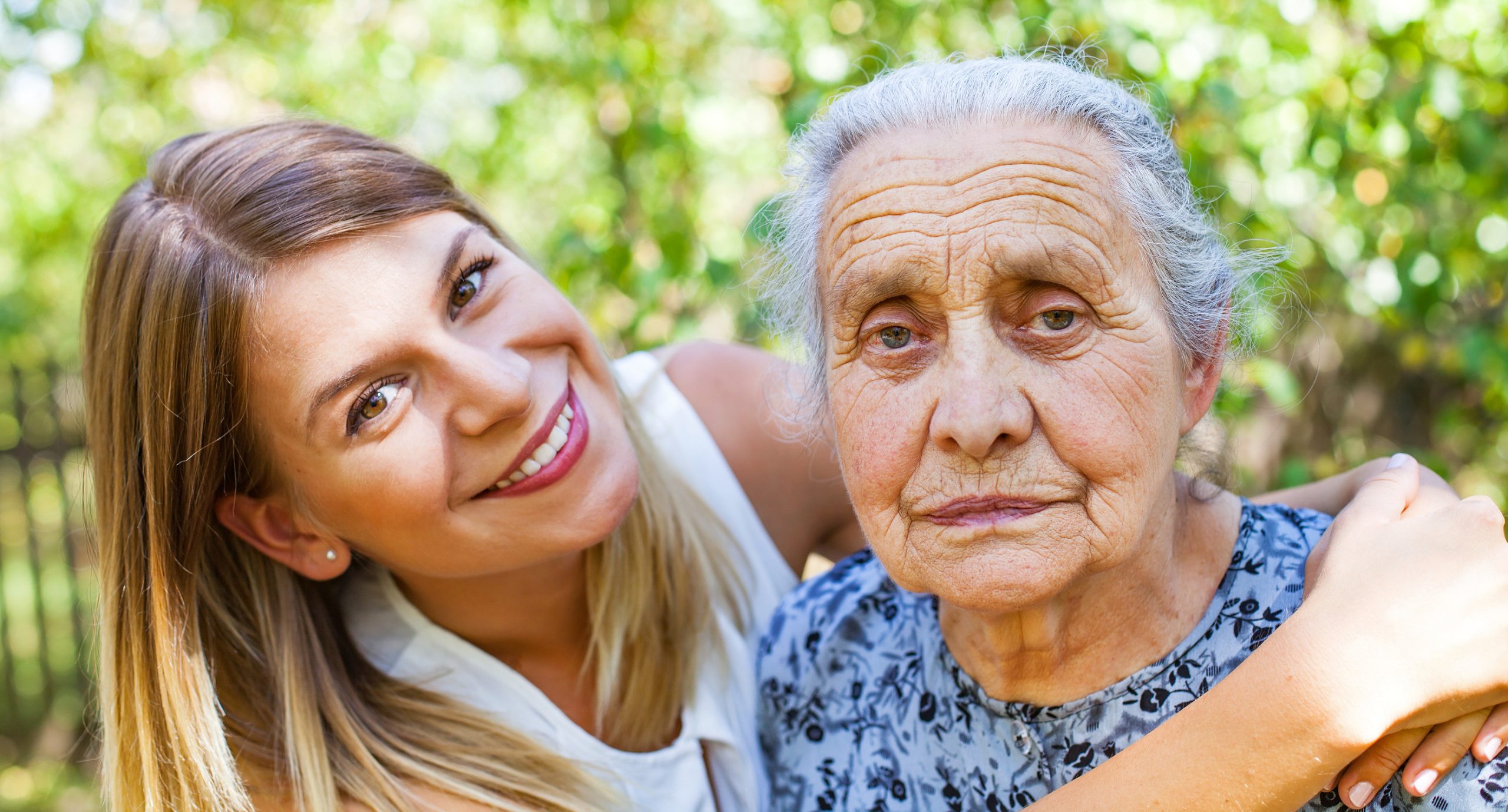 Close up picture of senior disabled woman with loving granddaughter in the garden